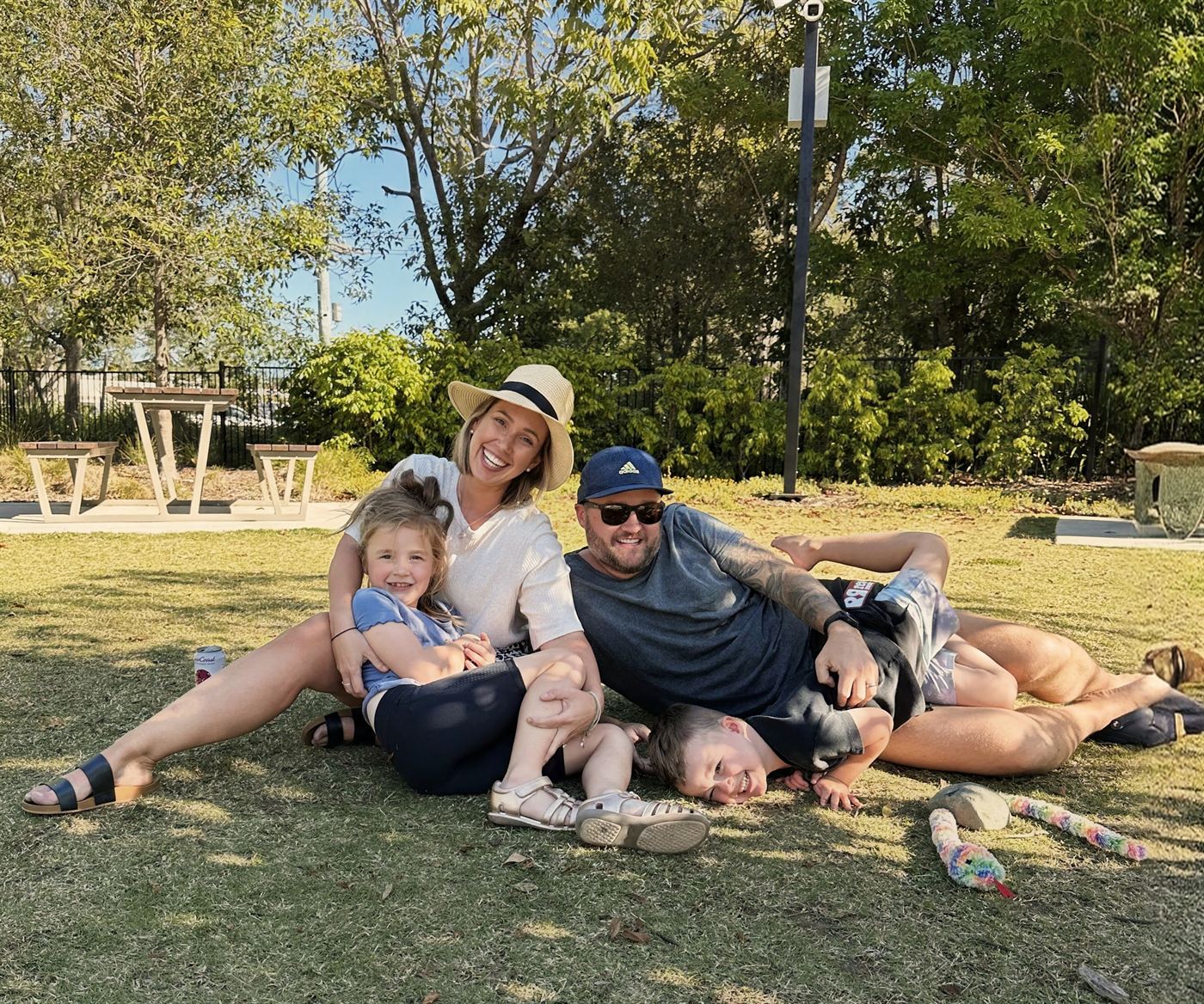 Leah laughing on the grass in a park with her husband and their two children